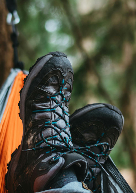 Kuvassa retkeilijä huilaa metsässä riippumatossa, vain kengät näkyvät.