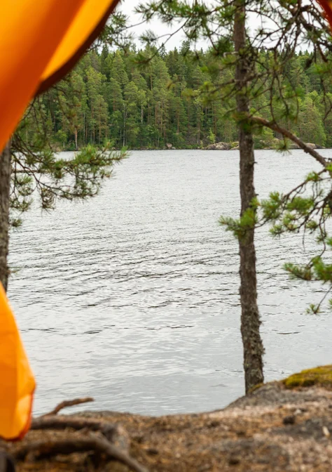 Kuva otettu teltan avoimesta oviaukosta, ulkona näkyy kalliota ja järvi.